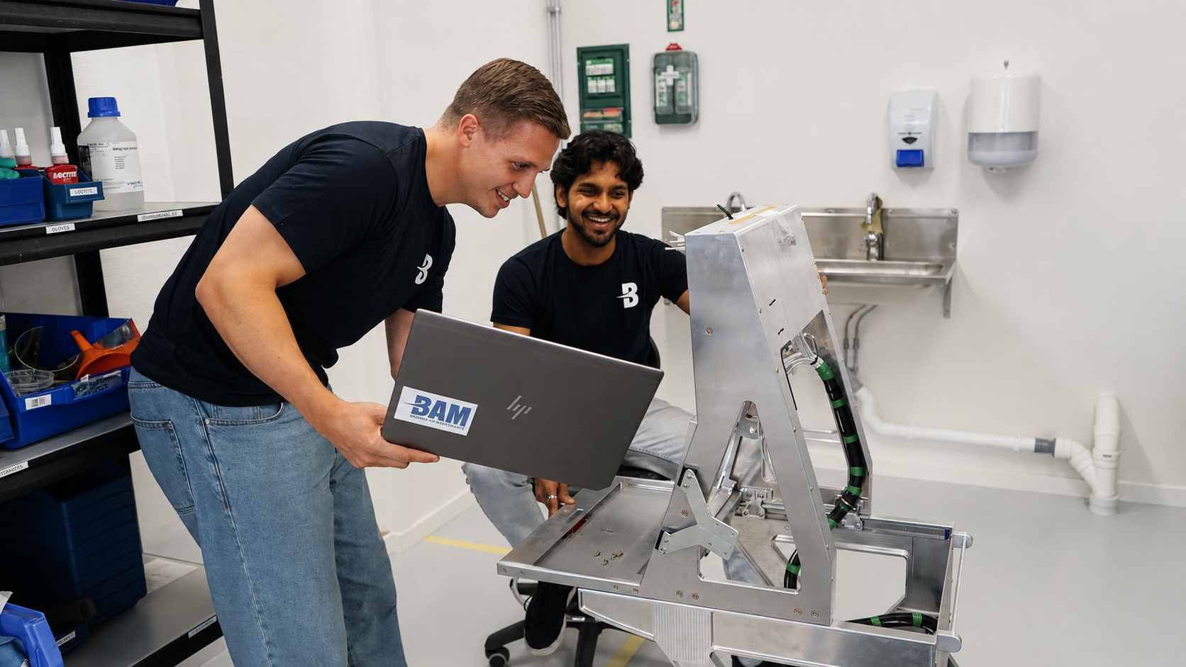 BAM engineers checking design data on a laptop beside an aluminium aircraft console assembly in the production workshop