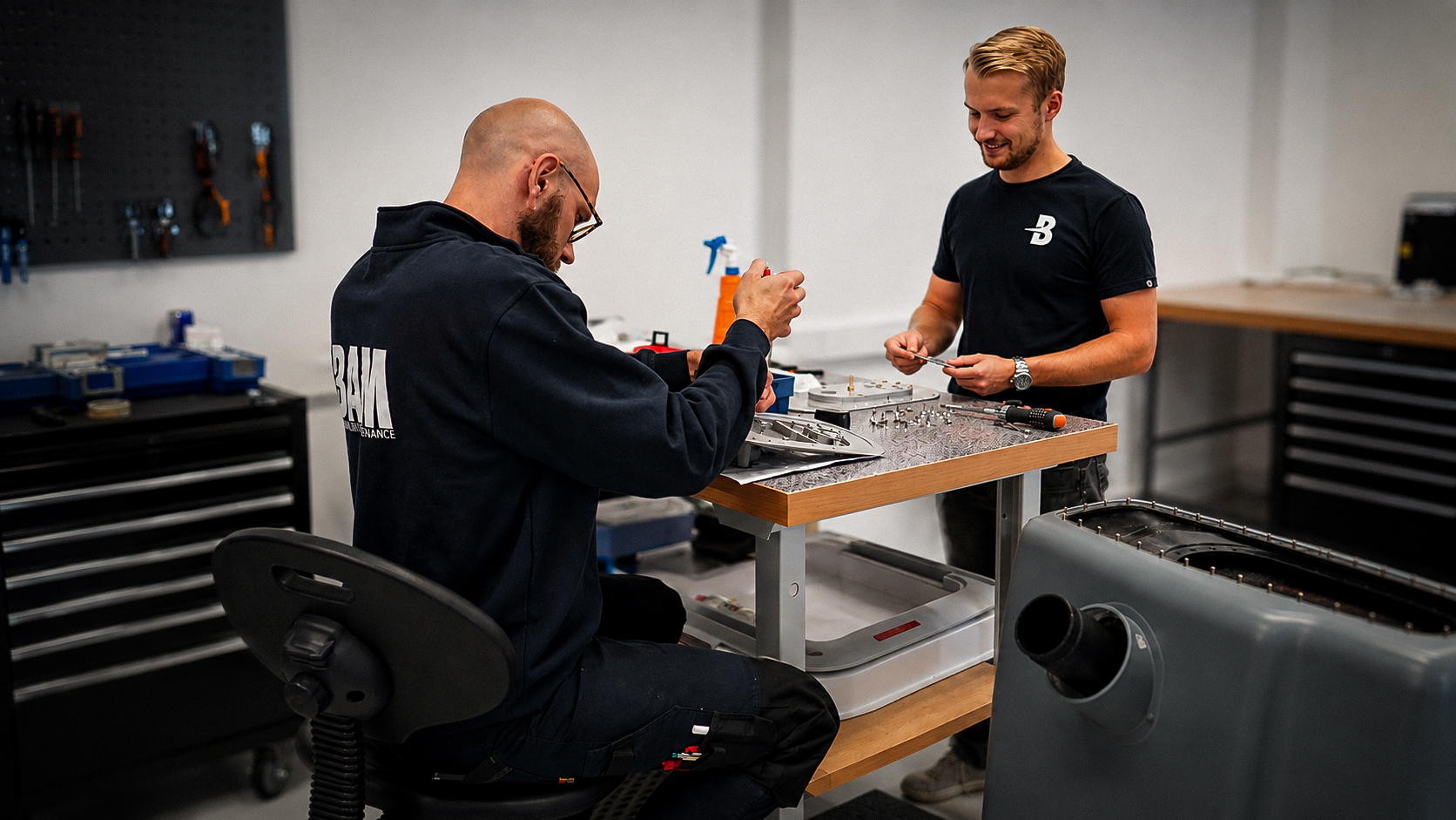 BAM technicians assembling an aircraft component at a workbench in the Part-21 production workshop
